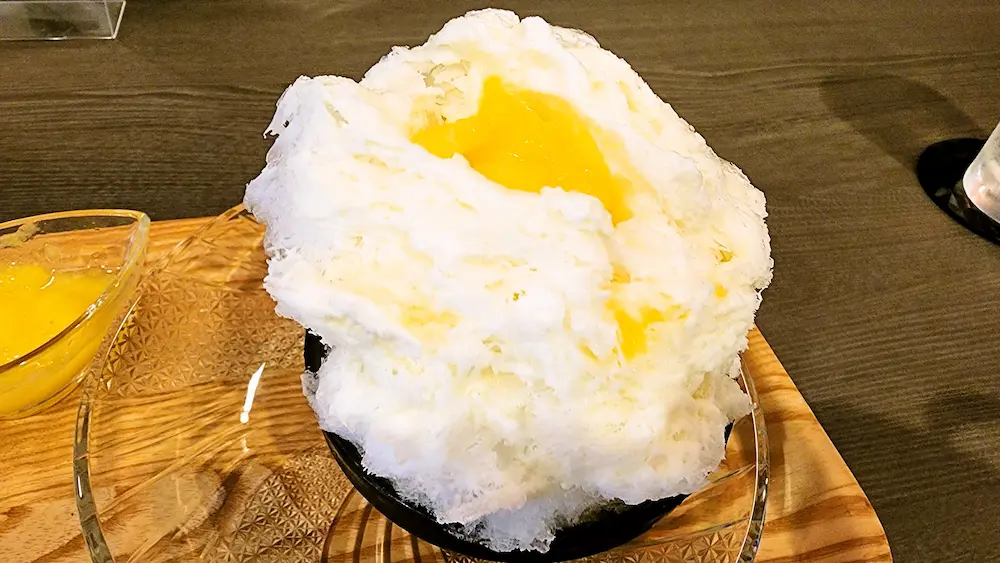55MAHALOのかき氷にパイナップルソースをかける